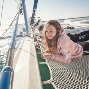 Girl smiling while laying on trampoline on catamaran