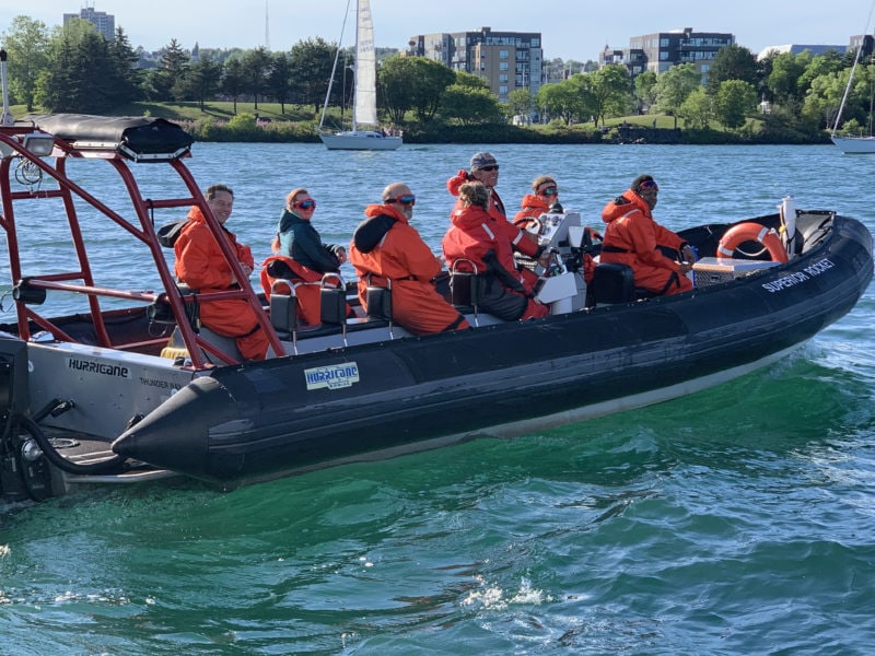 Zodiac passengers on blue water of the Thunder Bay Marina